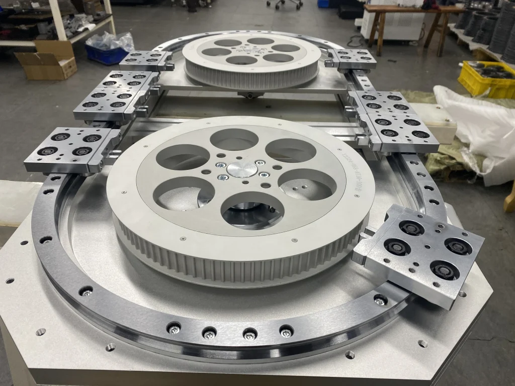 Close view of an oval track assembly with large toothed pulleys and carriage plates