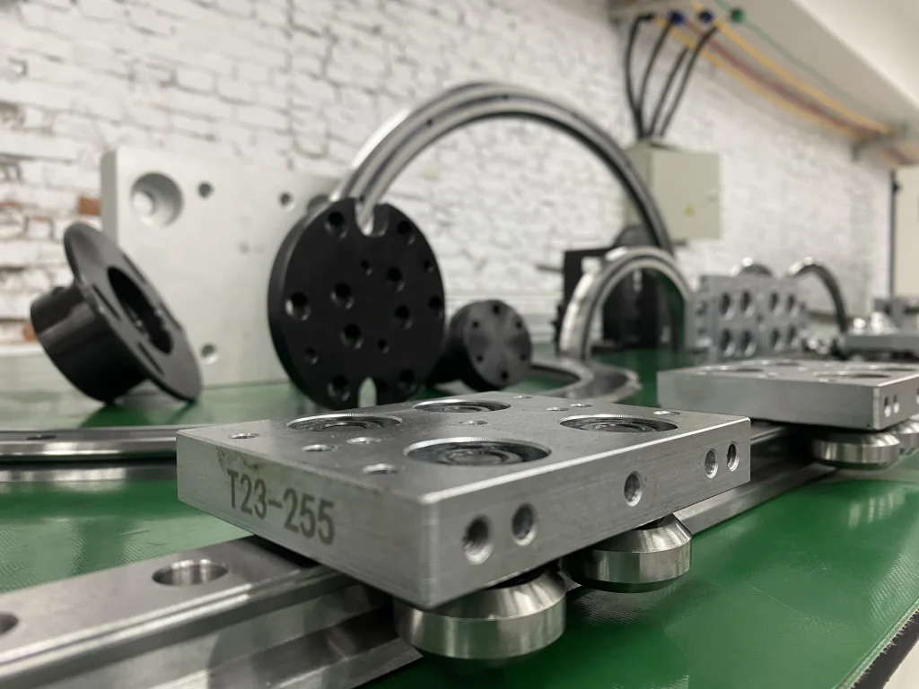 Close view of a carriage plate, rollers and fasteners on a straight guide section
