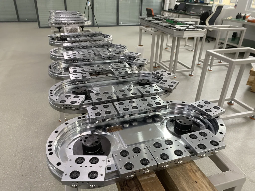 A row of compact oval track modules with carriage plates in the assembly area