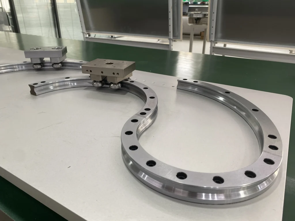 Open curved guide segment beside a matching curved path with a carriage