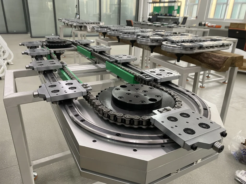An oval track assembly with a chain drive, carriage plates and straight working sections