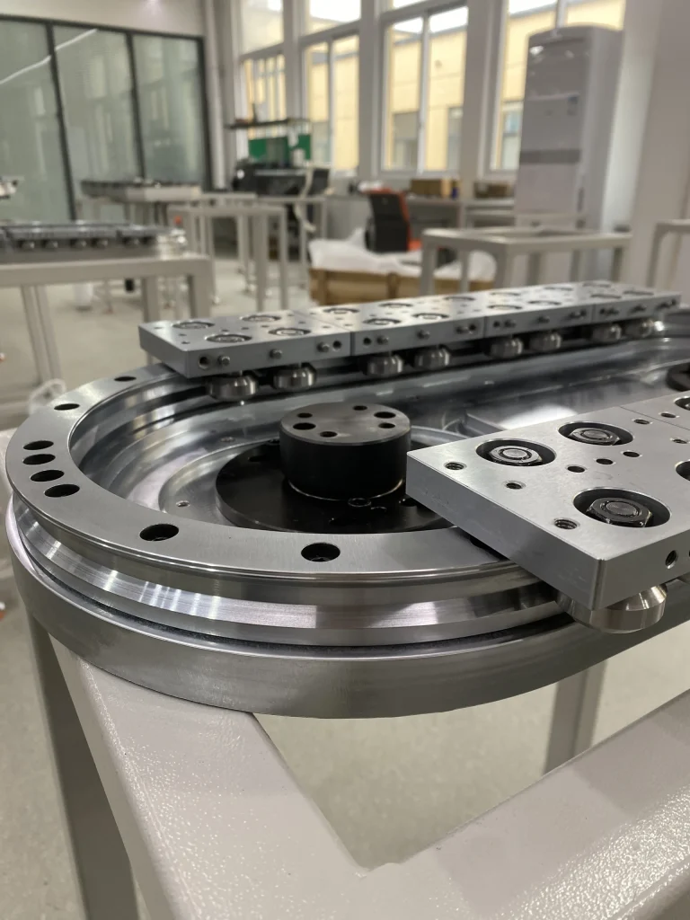 Close view of a curved return rail, drive wheel and carriage plates