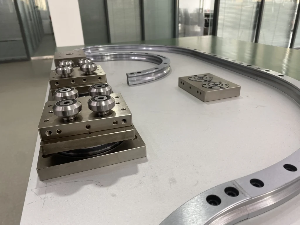 A roller carriage assembly on a curved guide path with mounting interfaces visible