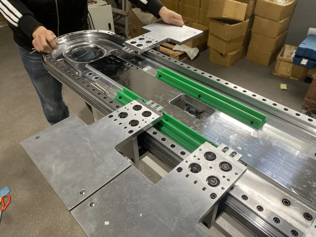 Hands-on assembly of an oval track with green guide components and fixture plates